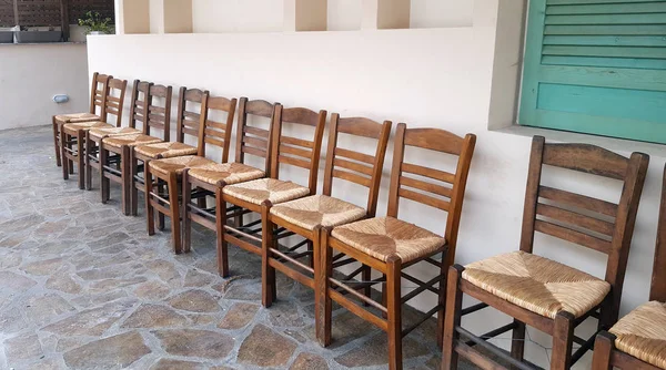 Řada dřevěných židlí na přední straně domu v Řecku — Stock fotografie