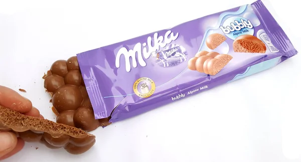 THESSALONIKI, GRÈCE - 02 FÉVRIER 2018 : Main avec du chocolat Milka sur fond blanc . — Photo