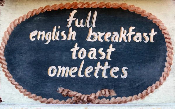THASSOS, GREECE - September 13, 2015: A wooden sign outside a restaurant, full english breakfast, toast, omelettes — стоковое фото