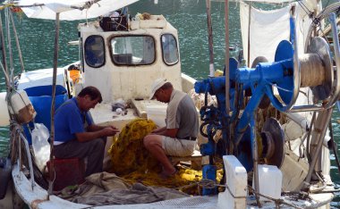 Taşöz, Yunanistan - 15 Eylül 2015: balıkçılar balık ağları içinde onun tekne balıkçılık sonra toplamak