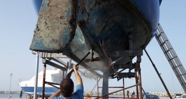 Adam alt kısmında bir yelkenli yüksek basınçlı su ile Temizleme