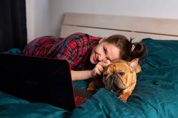 Ung Flicka Och Hennes Hund Franska Bulldog Arbetar Sängen Bärbar Royaltyfria Stockbilder