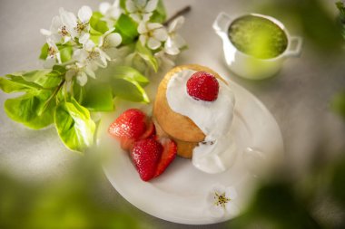 Güneşli bir bahar gününde kahvaltı için Japon gözlemesi. Çiçekli armut dalları ve çilekli güzel bir kahvaltı.