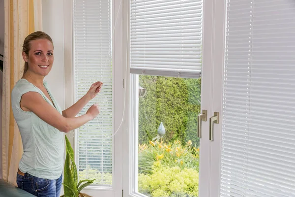 Woman lets down blinds — Stock Photo, Image