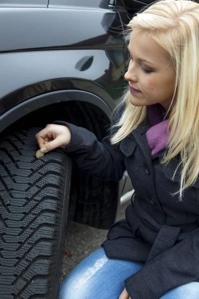 Vrouw maatregelen tire tread van een auto band — Stockfoto