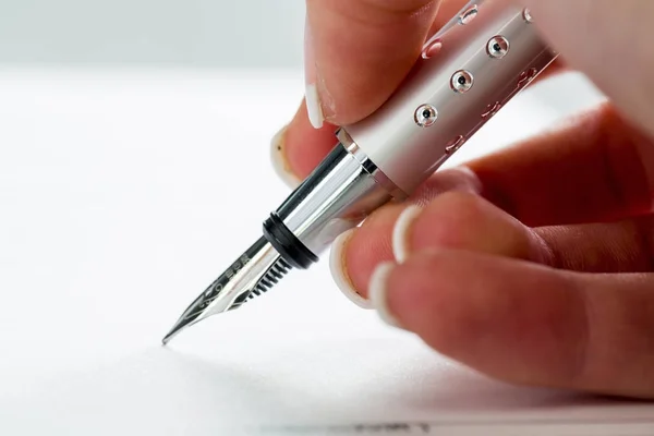 Рука с перьевой ручкой при подписании — стоковое фото