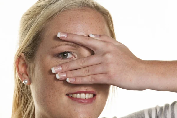 Vrouw kijkt door vingers van haar hand — Stockfoto