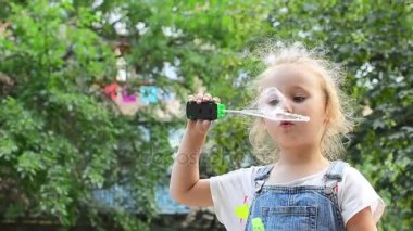Küçük kız sabun köpüğü üflüyor