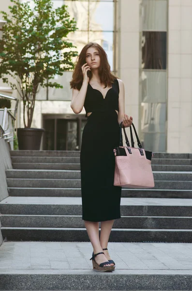 Ofis binaları arka planda, sokakta cep telefonuyla çalışan bir yönetici.