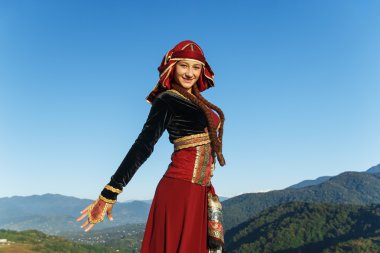 genç kadın Gürcü Ulusal giysileri dağlar açık havada yaz güneşli dans