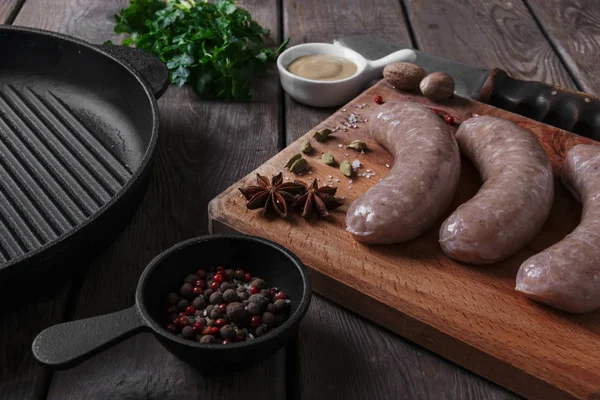 Домашняя сырая колбаса со специями на доске — стоковое фото