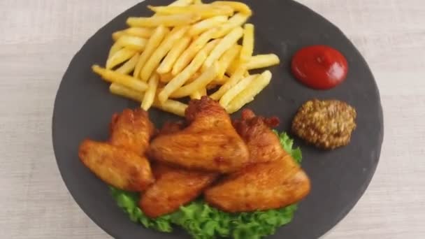 Kızarmış tavuk kanatlı patates kızartması sosu taş bir plaka üzerinde döner — Stok video