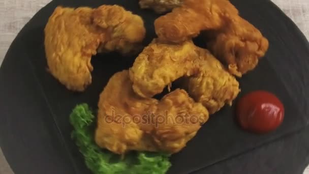 Τηγανιτές φτερούγες κοτόπουλου σε κουρκούτι με σάλτσα σε μια πέτρινη επιφάνεια περιστροφή — Αρχείο Βίντεο