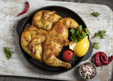 Limonlu ve otlu dökme demir bir tavukta pişirilmiş tütün tavuğu.