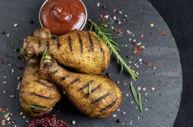 Kızarmış tavuk budu ve siyah taş bir yüzey üzerinde kırmızı sos.