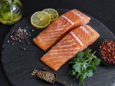 Çiğ somon balığı fileto, baharat ve bezelye filizleri bir taş yüzeyde bulunur.