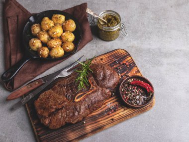 Kemikli ızgara biftek, tavada kızarmış patates, baharatlar.