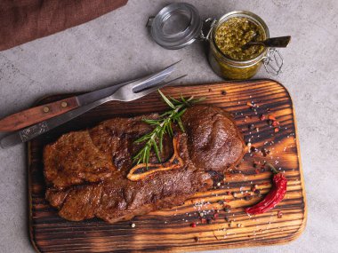 Kesme tahtasında kemikli ızgara biftek, baharatlar.