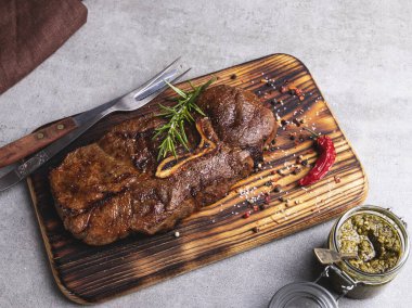 Kemikli ızgara biftek. Kesme tahtası, baharatlar, sos sosu.