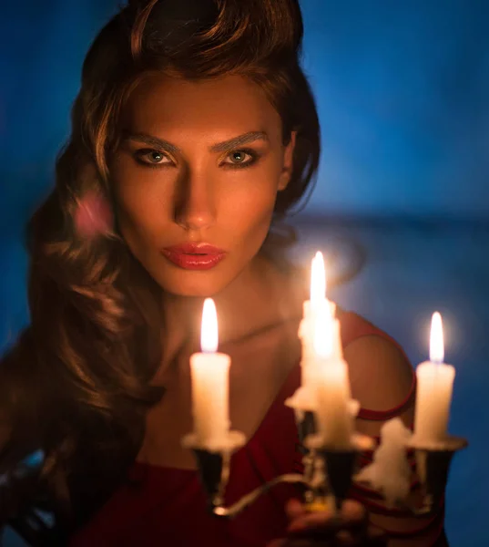Mulher olhando em velas vermelhas na noite fabulosa — Fotografia de Stock