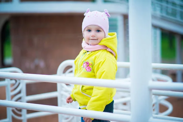 Grappige babymeisje in een gele vacht en roze hoed — Stockfoto