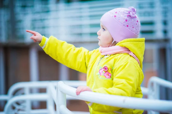 Grappige babymeisje in een gele vacht en roze hoed — Stockfoto
