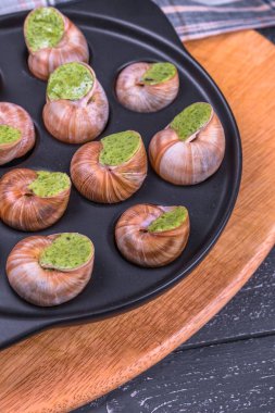 Ahşap arka plan üzerinde bir tabakta escargots de Bourgogne