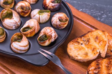 Ahşap arka plan üzerinde bir tabakta escargots de Bourgogne