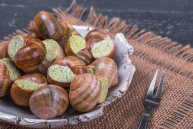 Ahşap arka plan üzerinde bir tabakta escargots de Bourgogne