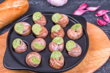 Ahşap arka plan üzerinde bir tabakta escargots de Bourgogne