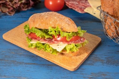 Salamlı sandviç ve ahşap arka planda salata.