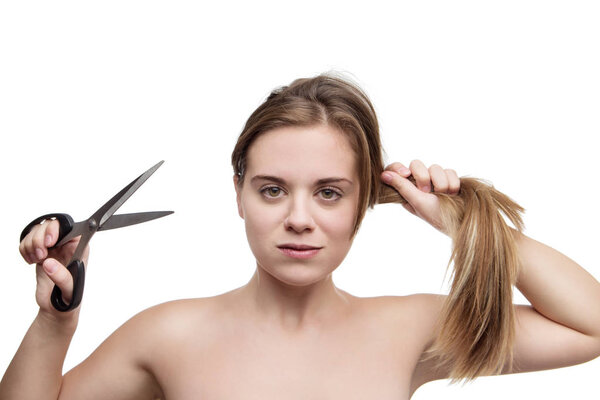 young woman with long hair cutting it of with a pair of scissors having a bad hair day