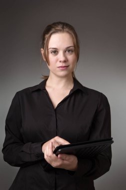 Studio gri bir arka plan üzerinde bir bilgisayarı kullanan genç iş kadını vurdu