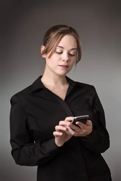 Genç Kadını Manifatura Bir Cep Telefonu Üzerinde Gri Bir Arka — Stok fotoğraf
