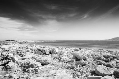 Malta 'daki kayalık sahil bulutlu gökyüzü ile denize bakıyor.