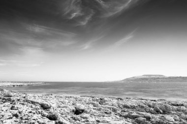 Malta 'daki kayalık sahil bulutlu gökyüzü ile denize bakıyor.