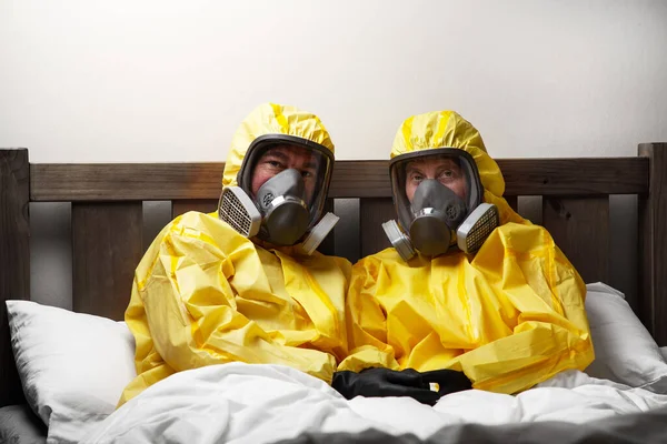 two people self isolating in bed being extra careful and wearing hazmat suit