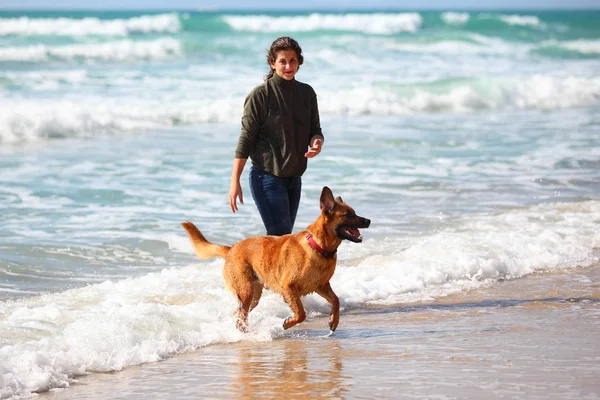 Adolescente menina com seu cão na praia . — Fotografia de Stock