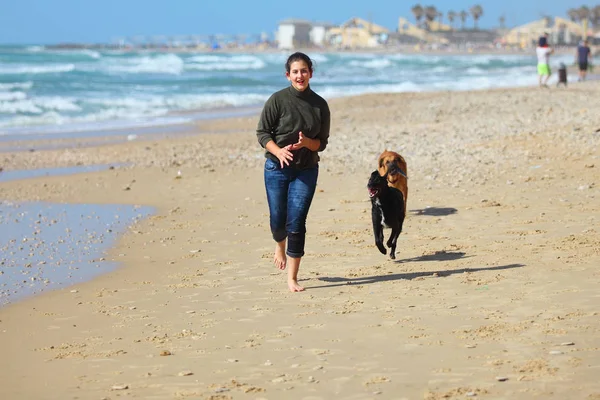 Adolescente brincando com seus cães na praia . — Fotografia de Stock