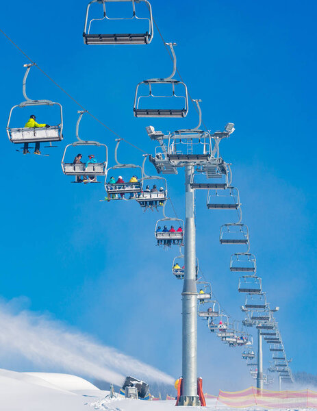 Bukovel, Ukraine - December 31, 2015: Skiers and snowboarders on a ski lift in Bukovel. Bukovel is the most popular Ukranian mountain resort.