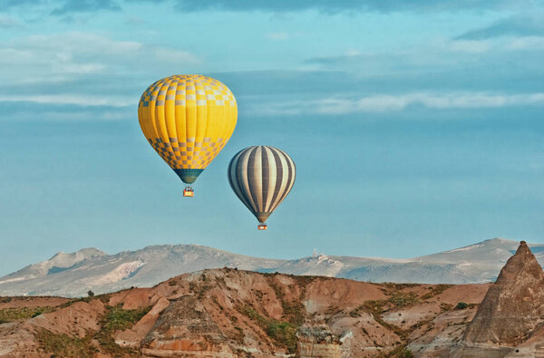 Hot air balloons over mountain landscape in Cappadocia, Goreme National Park Turkey.