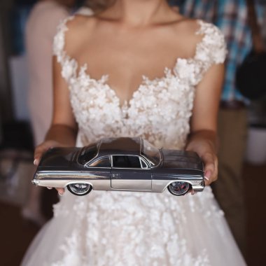 Gelin bir retro araba modeli ellerinde tutuyor