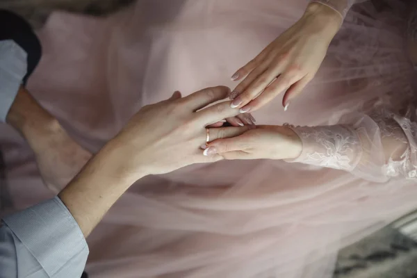 Hands of wedding couple putting golden rings to finger of each other. — Stock Photo, Image