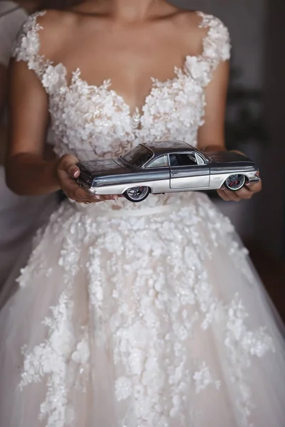 Die Braut hält ein Retro-Automodell in den Händen — Stockfoto