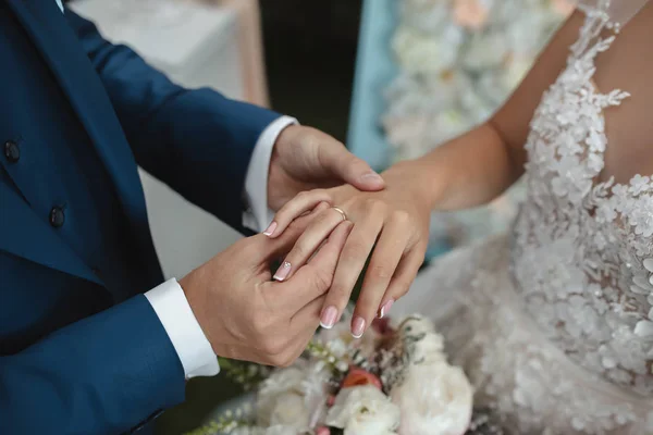 Hands of wedding couple putting golden rings to finger of each other. — Stock Photo, Image