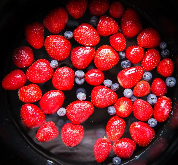 Strawberries and blueberries in water — Stock Photo, Image