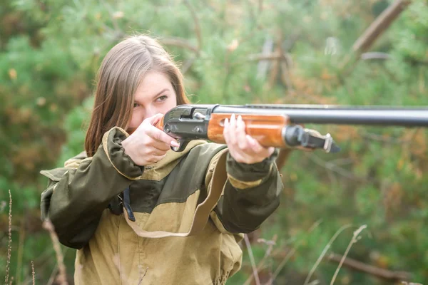 Retrato de uma bela jovem caçadora em roupas de camuflagem na floresta caduca na natureza com uma arma — Fotografia de Stock