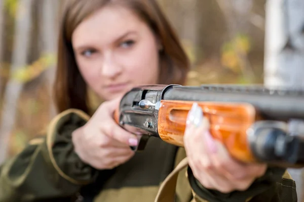 Retrato de una hermosa joven cazadora en ropa de camuflaje en el bosque caducifolio en la naturaleza con una pistola — Foto de Stock