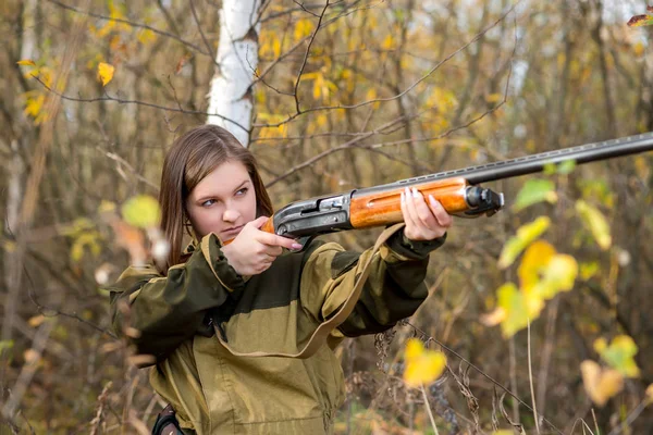 Portrait of a beautiful young girl hunter in camouflage clothes in the deciduous forest in nature with a gun — Stock Photo, Image