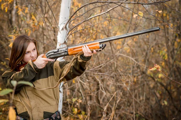 Retrato de una hermosa joven cazadora en ropa de camuflaje en el bosque caducifolio en la naturaleza con una pistola — Foto de Stock